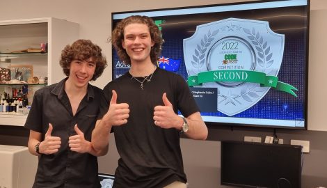 two students smiling with thumbs up