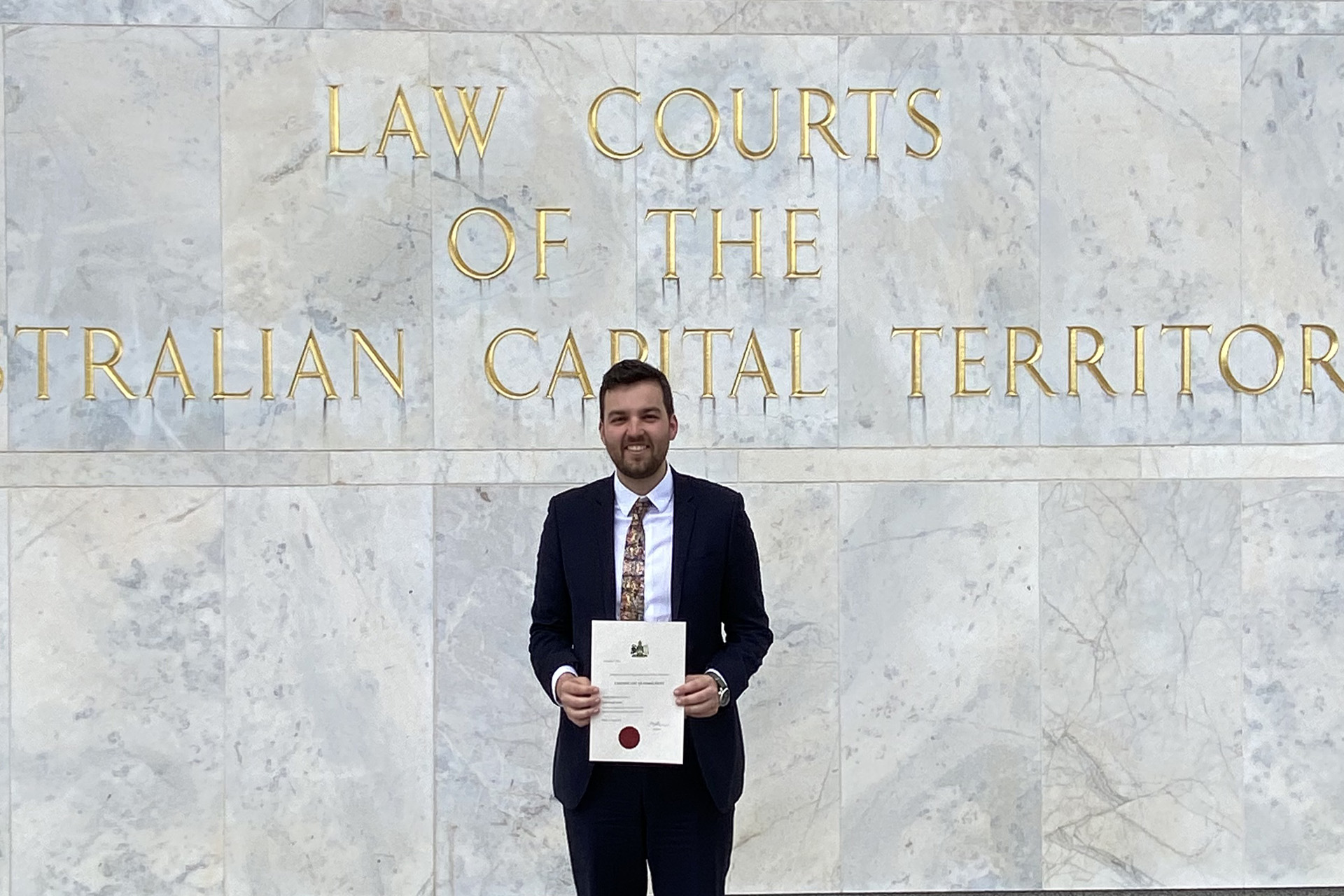 man standing outside court holding certificate