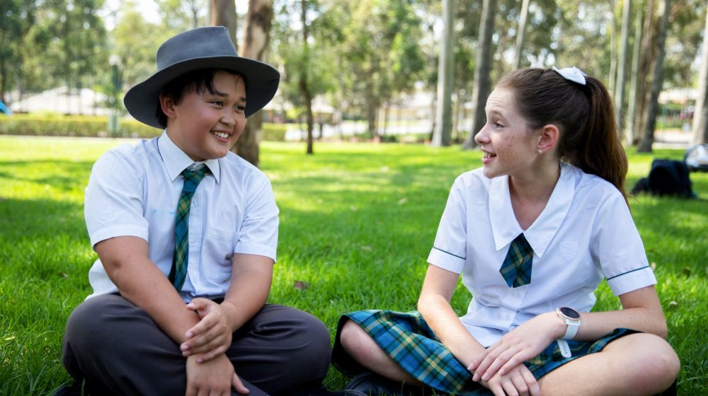 two students chatting on grass